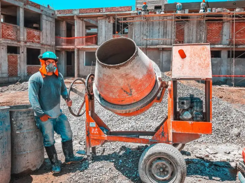 Worker beside a concrete mixer on a residential construction site
